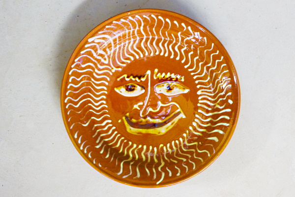 Plat del sol content i rialler. Terra vermella, engalbes i vernís. Torn. Decoració a xeringa. Josep Vilà Clara, 1959. Ø 24 cm. TM. 10402. | © Ferran Vilà-Clara Grasiot