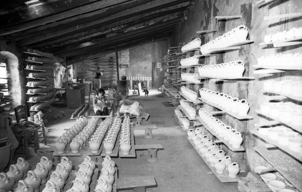 Dolors Guerra decorant una peça. Al seu volt, damunt les posts, multitud de peces esperen el seu torn (1990) | © Quim Tor