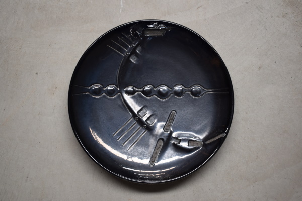 Plata. Terra vermella, engalba i vernís metal·litzat amb textura. Estec i modelatge manual. Josep Vilà-Clara Garriga, 1980. Ø 33 cm. Col·lecció particular.