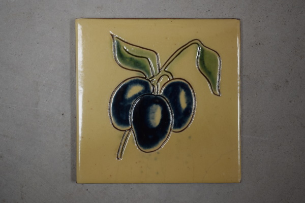 Rajoles de les fruites i les verdures. Terra vermella, engalbes i vernís. Galetera. Dibuix ratllat i xeringa. Josep Vilà Clara, 1957. 15x15 cm. Col·lecció particular.